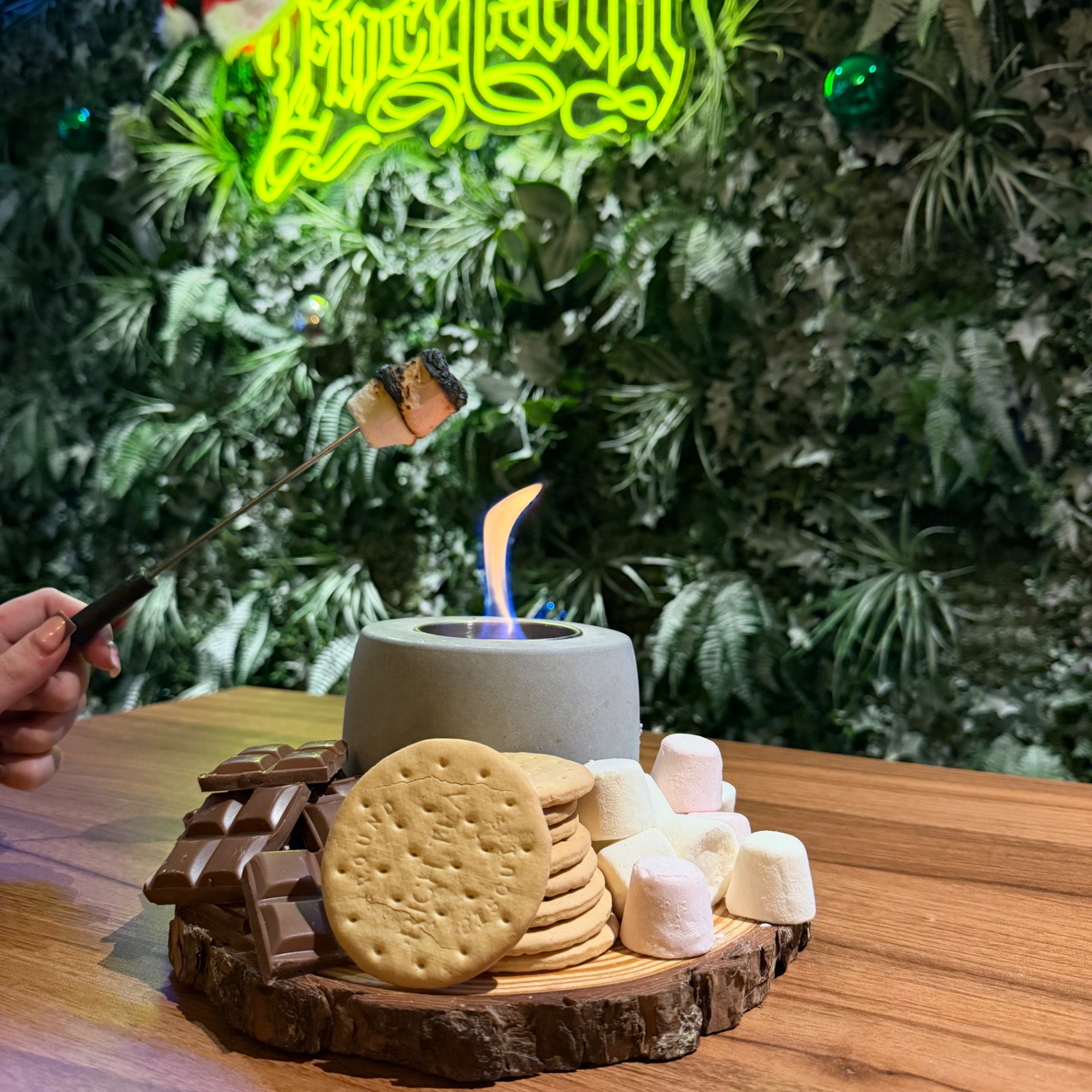 Toasting marshmallows over a table flame with chocolate and biscuits