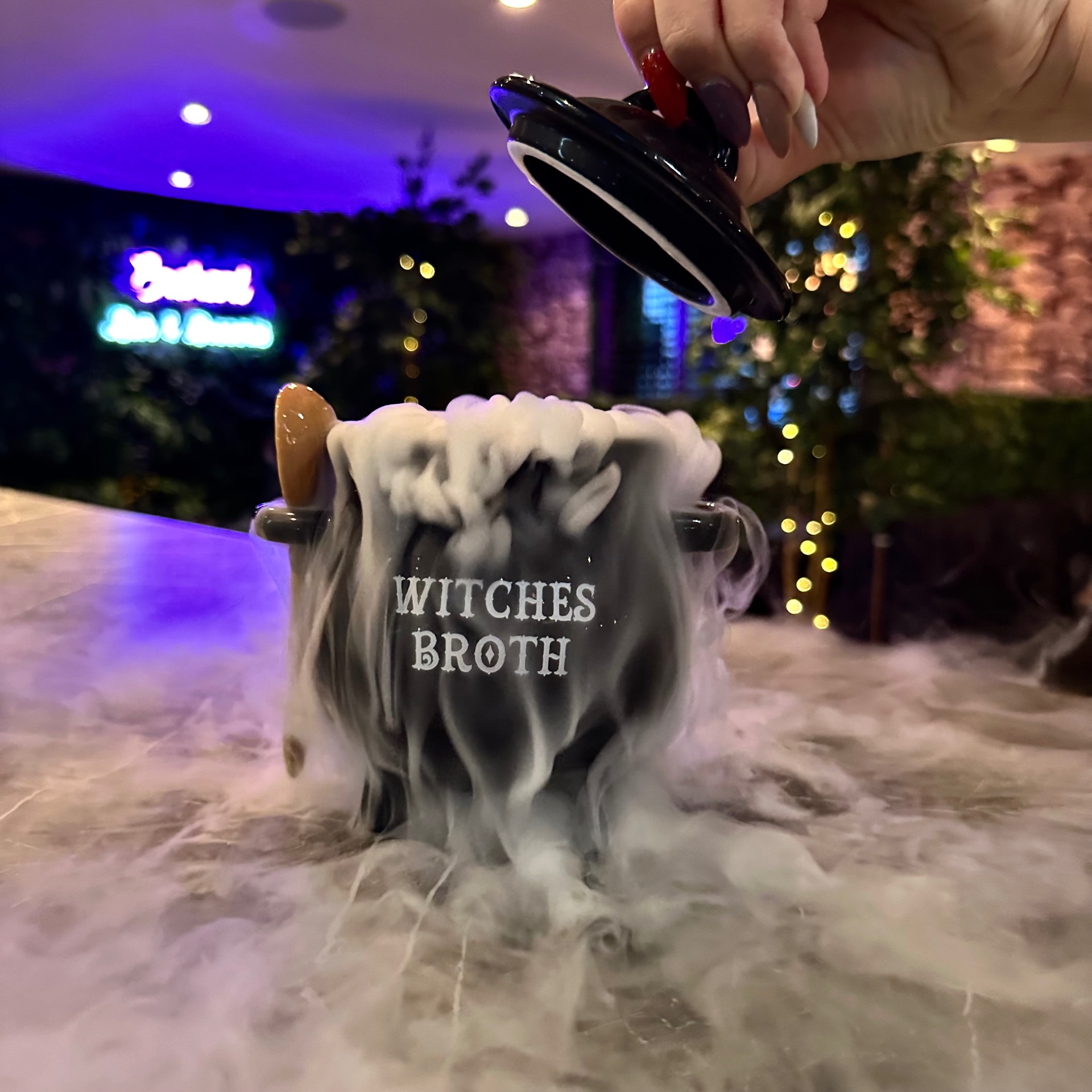 Lid lifted off the Witches Broth cauldron as smoke pours over the bar
